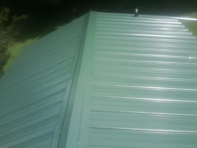 New green metal panels meeting at the ridge of a roof — Flat Roof Repair work by our crew in Temple Hills