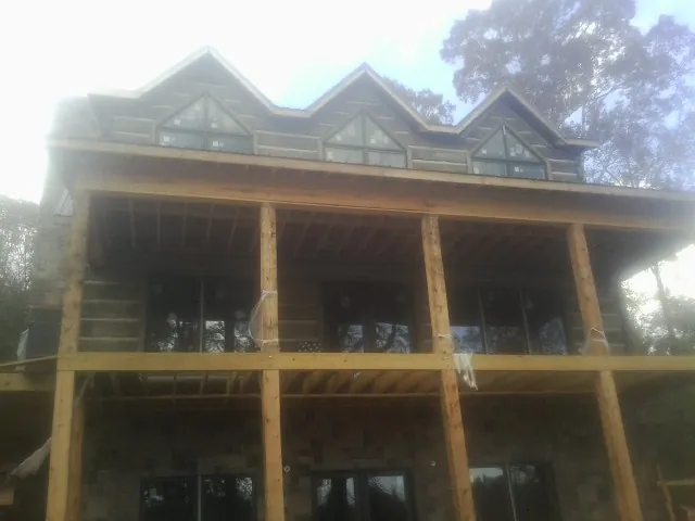 Dormers and porch framing on a large log home under construction — Roof Coating work by our crew in Temple Hills