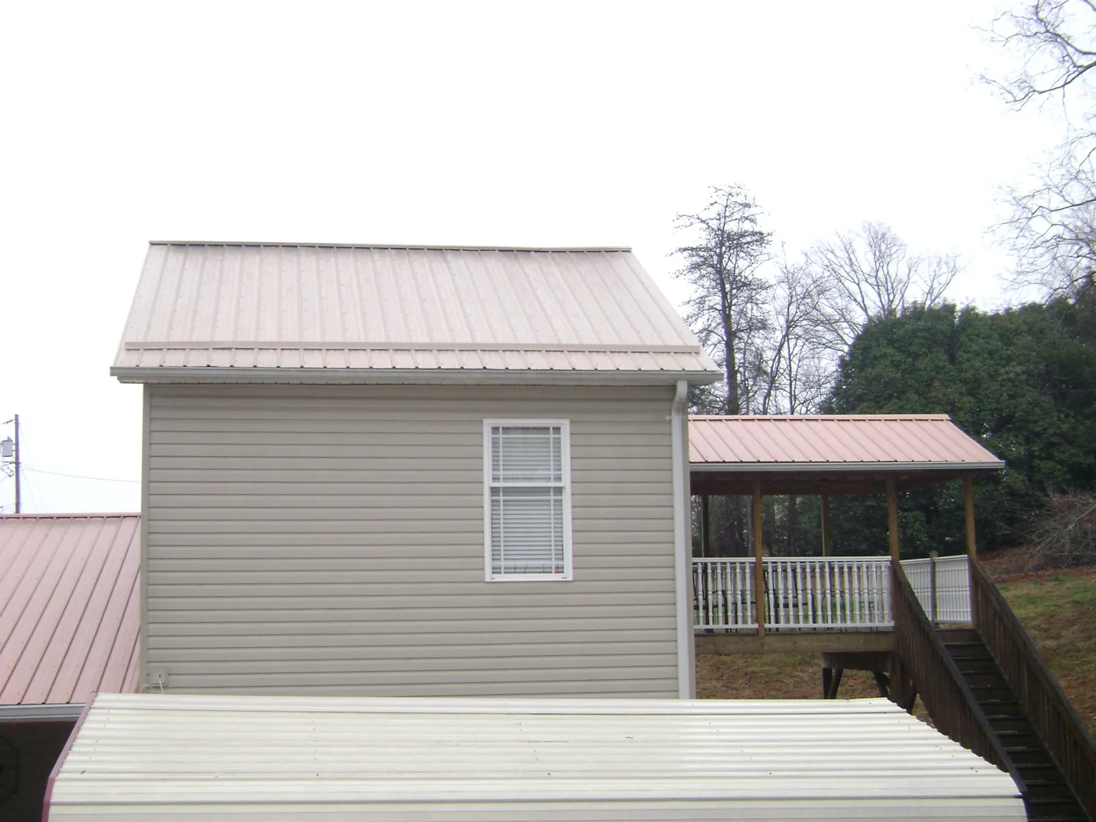 Tan metal roofs on a two story addition and attached porch, from a Roof Replacement job in Temple Hills
